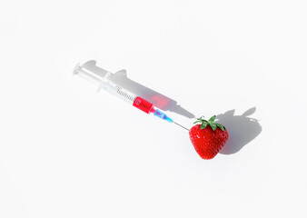 syringe with red liquid stuck in strawberries
