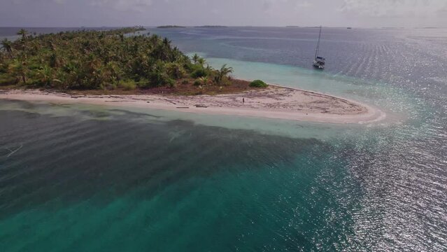 Drone shot from a remote island in San Blas Archipelago with a woman walking in the shore.