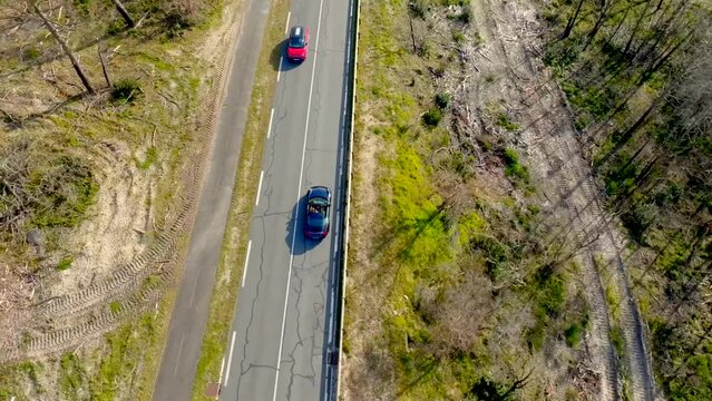Drone footage of a Porsche car driving in the pines along the french coast of Arcachon
