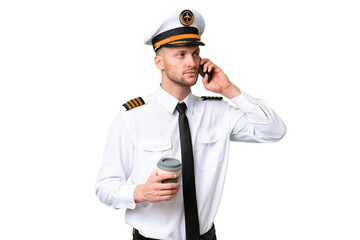 Airplane pilot man over isolated background holding coffee to take away and a mobile