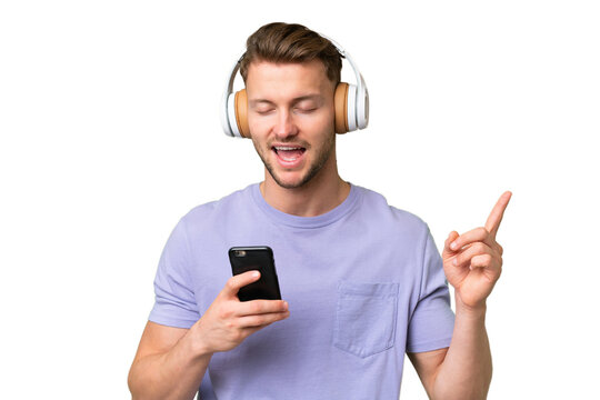 Young blonde caucasian man over isolated background listening music with a mobile and singing