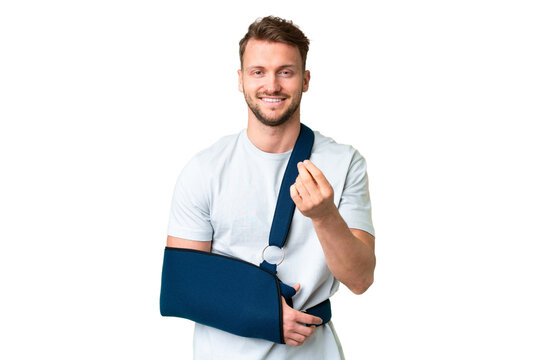 Young caucasian man with broken arm and wearing a sling over isolated chroma key background making money gesture