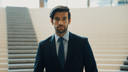 Portrait of Serious business man looking at camera while standing at stairs. Closeup of successful man staring at camera while wearing business suit. Happy executive manager look at camera. Exultant.