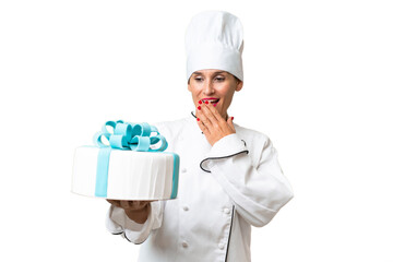 Middle-aged chef caucasian woman with a big cake over isolated background with surprise and shocked...