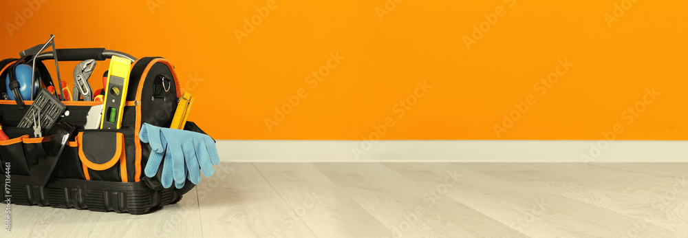 Sticker Bag with different tools for repair on floor near orange wall, space for text. Banner design