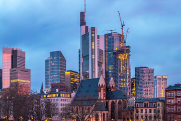 Sunrise on a river bank in the middle of a big city. Spring with a view of the skyline of the financial district and the historic buildings of Frankfurt, Hesse - obrazy, fototapety, plakaty