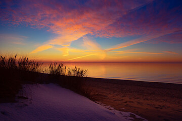A beautiful early spring landscape of Baltic Sea beach with grass silhouettes against the colorful...