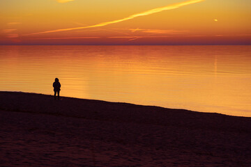 A beautiful sunset landscape of people enjoying evening at the Baltic sea beach. Human silhouettes...