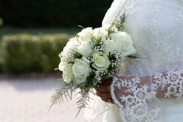 bride in lace gown holding a bouquet of white roses