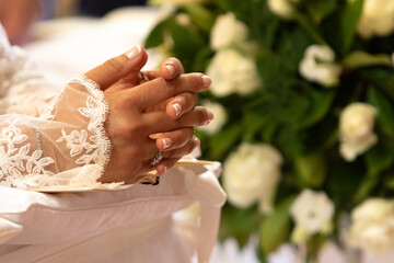 bride's hands clasped in prayer with wedding ring