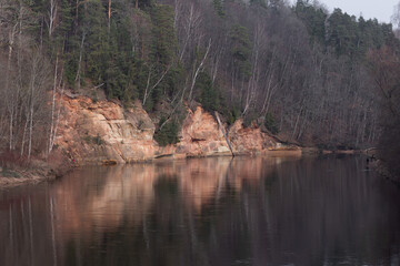 A beautiful sandstone cliffs at the river in Gauja National Park, Latvia. Springtime landscape of Northern Europe.
