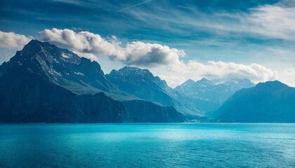 Rocky mountains and calm blue ocean water. Beautiful seascape. Blue sky with clouds.