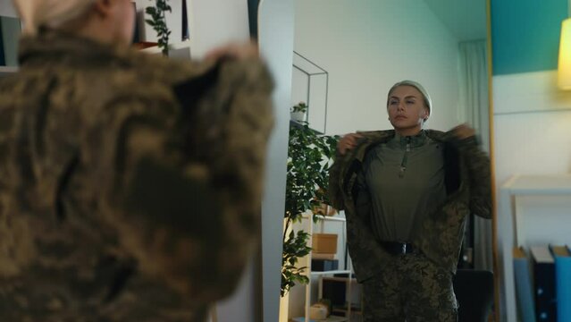 Female soldier getting dressed in front of a mirror, getting ready for work
