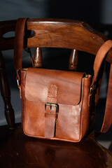 close-up photo of brown messanger leather bag on a wooden chair