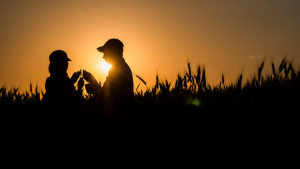 Silhouettes of two farmers in a wheat field.