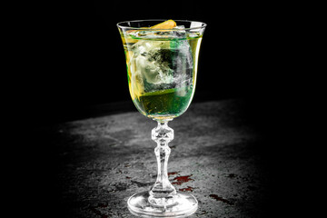 refreshing cocktail with lemon and mint in an elegant glass, highlighted against a dark background