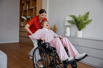 Crazy woman caregiver riding fast elderly woman patient on wheelchair