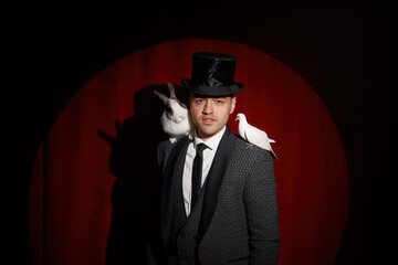 Elegant mysterious illusionist showing tricks with dove and rabbit