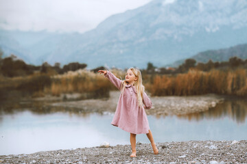 Child girl walking dancing barefoot outdoor 4 years old stylish kid wearing organic muslin dress fashion clothing family lifestyle lake and mountains harmony with nature