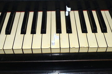 Fototapeta na wymiar 2 3D printed eighth notes in plastic PLA, lying on an antique piano in black color