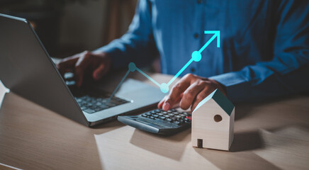 broker, diagram, residential, increase, insurance, real estate, management, financial, mortgage, property. A man is using a laptop and a calculator on a table. and a blue arrow is pointing upwards.