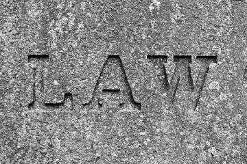 stone wall texture with Law carved into the rock in black and white