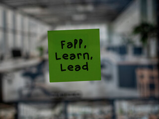 Post note on glass with 'Fall, Learn, Lead'.