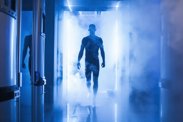 Naklejka premium A sci-fi scene with a silhouette of a male figure emerging from a cylindrical cryotherapy chamber surrounded by fog, evoking a sense of advanced technology