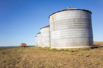 Fototapeta na wymiar Agricultural Storage Vintage Silos and an Old Water Cart in a field