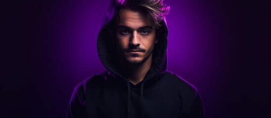a man in a black hoodie is standing in front of a purple background . High quality