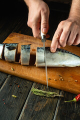 The chef cuts raw mackerel fish on a cutting board before preparing the dish. Low key concept for cooking fish menu. European cuisine