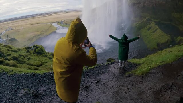 Tourist people making photos on tour visiting a Seljalandsfoss waterfall in Iceland, slow motion