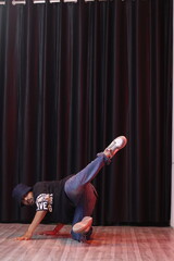 An Indian Hip Hop Dancer Boy Wearing over sized T-Shirt and loose jeans, dancing and posing in front of black curtain, dancer, freezes
