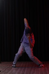 An Indian Hip Hop Dancer Boy Wearing over sized T-Shirt and loose jeans, dancing and posing in front of black curtain, dancer,  popping pose
