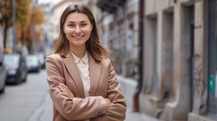 Fototapeta premium Portrait of a smiling young businesswoman standing with arms crossed in the street