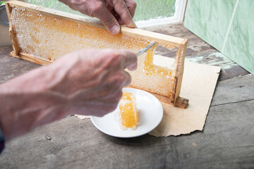 man cuts honeycombs from a honey frame with a knife for eating for tea, honey in honeycombs is good for the health