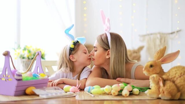 easter, mom and little daughter with bunny ears on their head are preparing for the holiday by having fun playing and spending time together, colorful eggs, lifestyle,