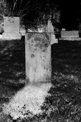 An old stone tombstone with a blank epithet in black and white film negative.