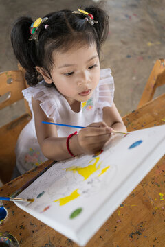 Asia beautiful little daughter drawing on canvas .