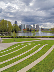 Landscaped recreation area with green lawn at Lafarge lake on cloudy day