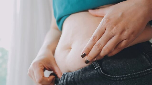Women body fat belly. Obese woman hand holding excessive belly fat. diet lifestyle concept to reduce belly and shape up healthy stomach muscle.