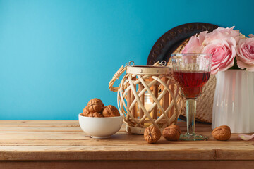 Jewish holiday Passover concept with wine glass, matzah and flowers on wooden table over blue background.