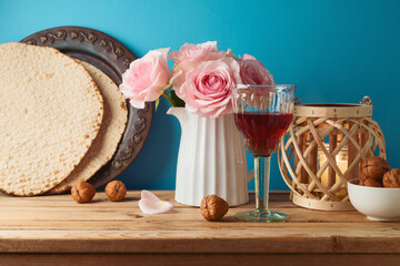 Jewish holiday Passover concept with wine glass, matzah and flowers on wooden table over blue background. - 771498422