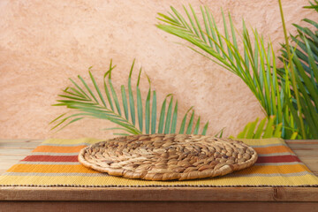 Empty wooden table with wicker place mat over wall with palm tree background. Summer picnic mock up for design and product display. - 771498424