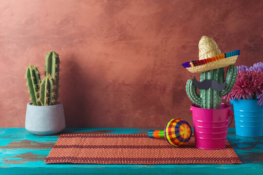 Empty wooden table with place mat  and cactus decoration over wall  background. Mexican party mock up for design and product display