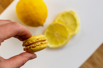 Traditional French sweets - lemon macaroons with lemon curd held in hand