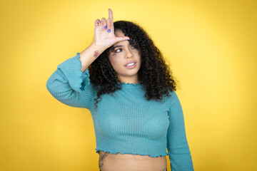 African american woman wearing casual sweater over yellow background making fun of people with...