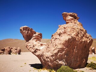Isolated rock formation in the Bolivia desert against a backdrop of a deep blue sky