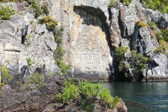 Ancient Maori rock carving set against the backdrop of Lake Taupo in New Zealand