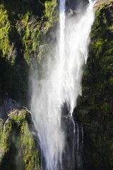 Stunning view of a waterfall cascading down a mountain cliff in Fjordland South Island, New Zealand.